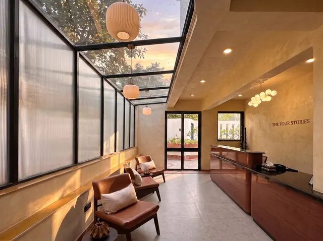 Skylit reception at The Four Stories with lantern pendants, leather lounge chairs and a wooden front desk