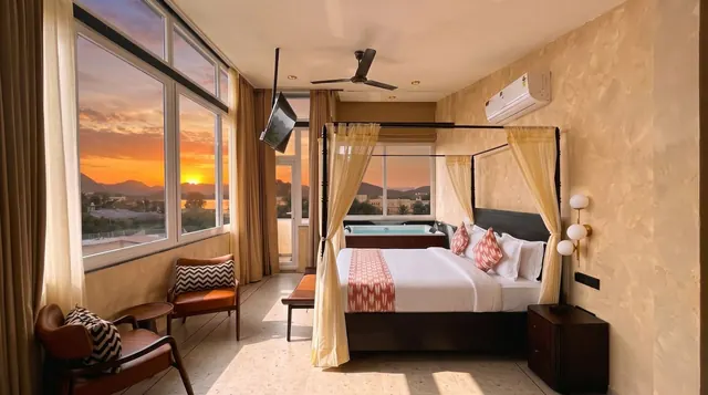 Lake View Suite with Jacuzzi in Udaipur: canopied bed, in-room Jacuzzi by the window and a sunset over the lake and hills